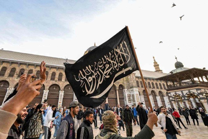  Manifestante segura a bandeira da Shahada islâmica, juramento da fé muçulmana, enquanto caminha no pátio da Mesquita dos Omíadas -  (crédito:  AFP)