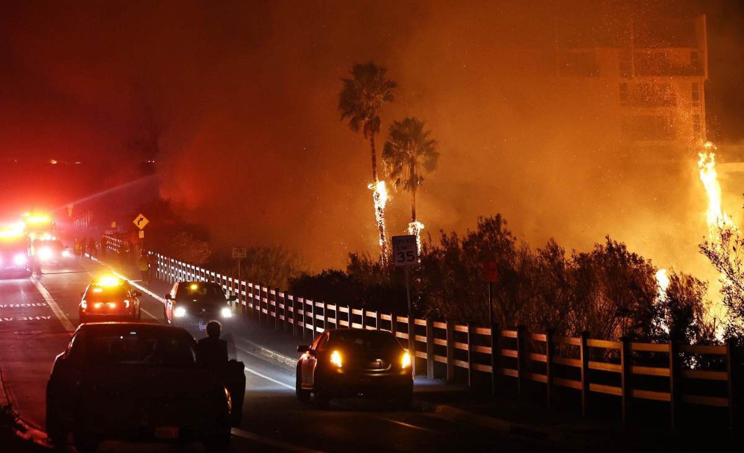 Bombeiros trabalham enquanto o Franklin Fire queima perto de um prédio em 10 de dezembro de 2024 em Malibu, Califórnia      