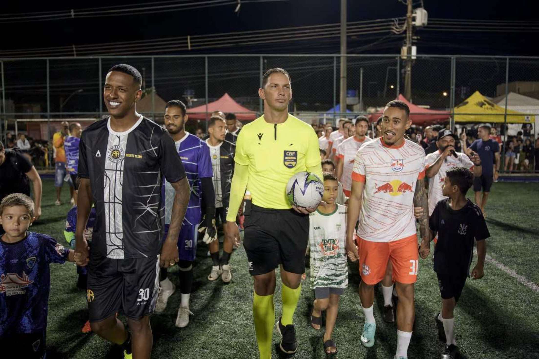 O jogo beneficente entre Amigos do Robert Renan e Amigos do Guilherme começou com uma entrada no campo society digna de Uefa Champions League