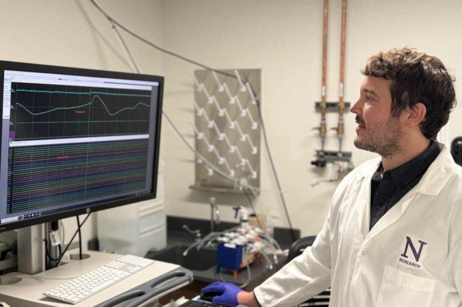 O autor correspondente Andrew Sheriff olha para um monitor de computador em um laboratório
