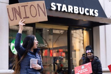 Steph Kronos, uma ativista pró-sindical, junta-se a trabalhadores, ex-funcionários e apoiadores da Starbucks segurando cartazes em apoio a uma greve       -  (crédito: SAUL LOEB / AFP)