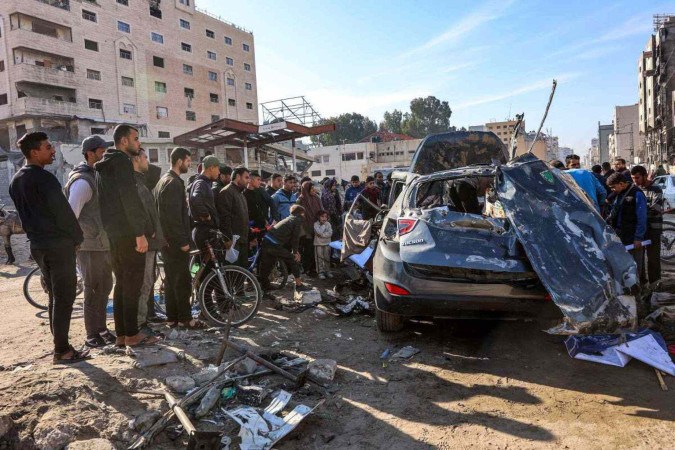 Pessoas inspecionam os restos de um veículo civil que foi atingido pelo bombardeio israelense ao longo da rua Jalaa, no centro da cidade de Gaza, em 22 de dezembro de 2024       -  (crédito: Omar AL-QATTAA / AFP)