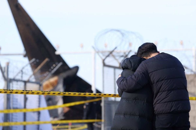 Parentes e amigos choram seus mortos no Aeroporto Internacional de Muan, a 288 quilômetros a sudoeste de Seul -  (crédito:  AFP)