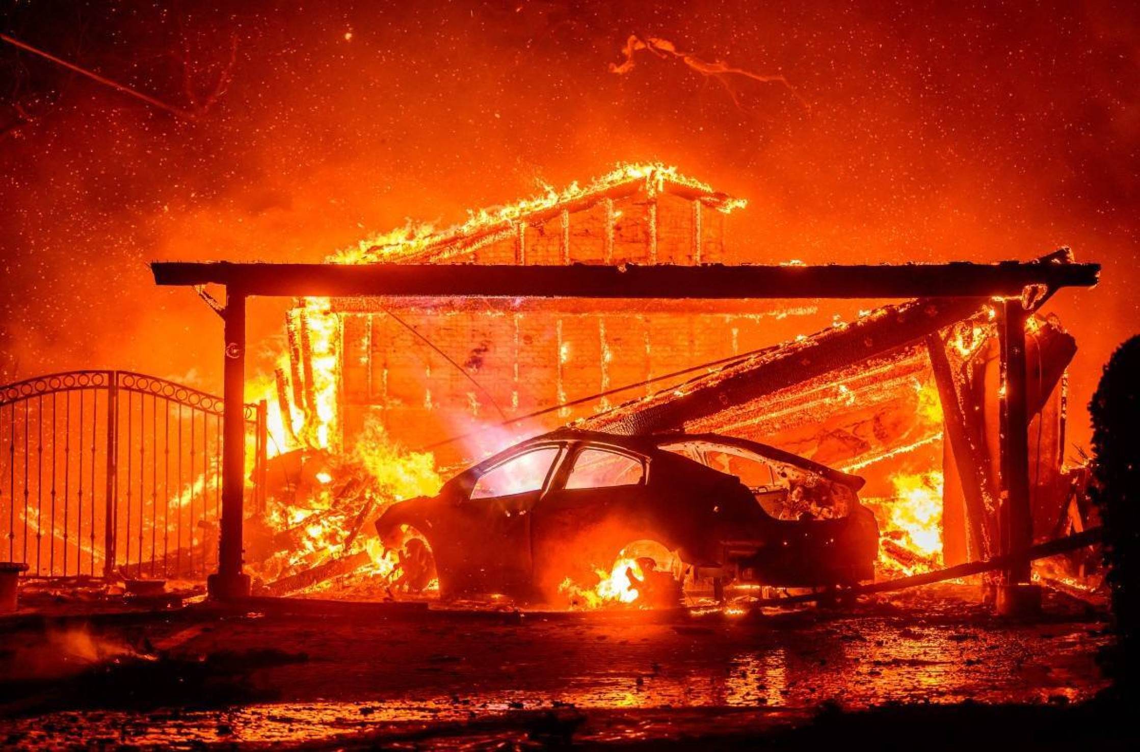  A car and home burn during the Eaton fire in the Altadena area of Los Angeles County, California on January 8, 2025. (Photo by JOSH EDELSON / AFP)       Caption 