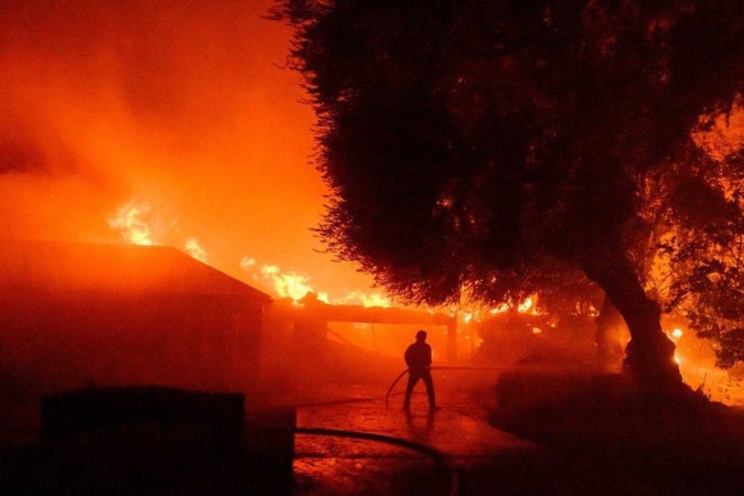 Bombeiro trabalha enquanto dezenas de casas continuam em chamas durante o incêndio em Eaton na área de Altadena, no condado de Los Angeles, na Califórnia -  (crédito: JOSH EDELSON / AFP)