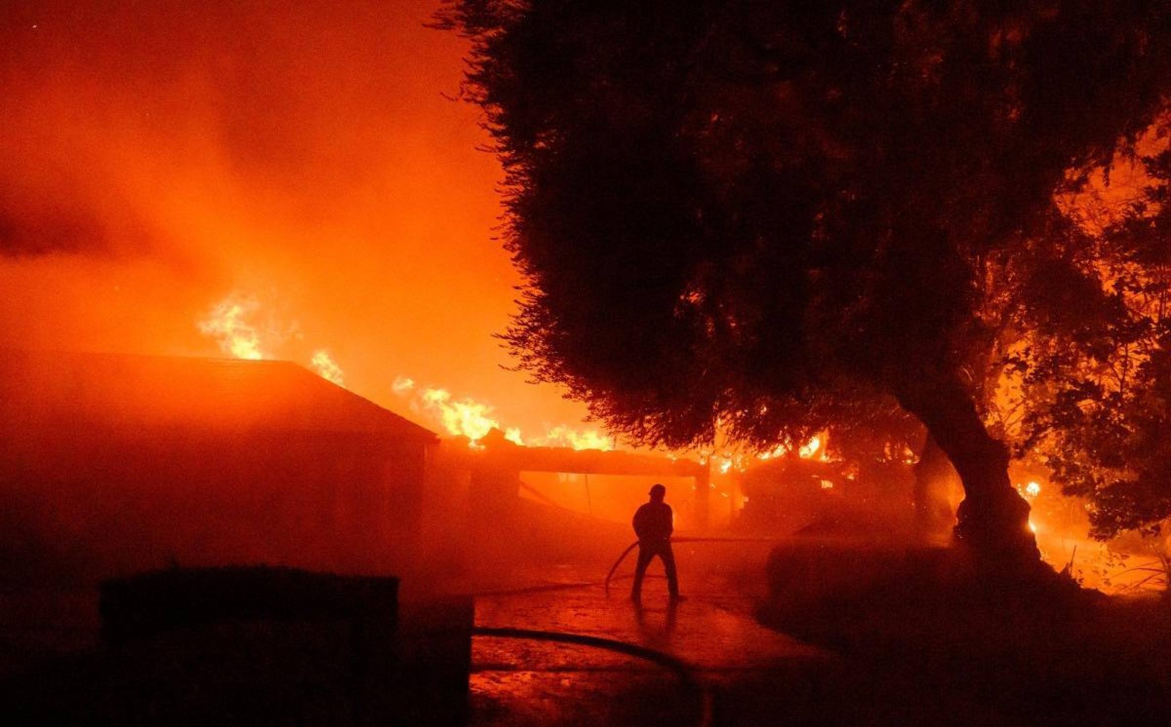 Um bombeiro trabalha no local enquanto dezenas de casas continuam em chamas durante o incêndio em Eaton na área de Altadena, no condado de Los Angeles, Califórnia, em 8 de janeiro de 2025.