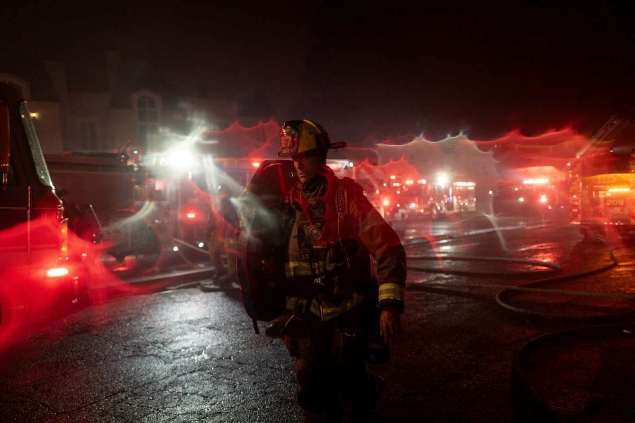 Um bombeiro carrega uma mangueira enquanto luta contra o incêndio em Palisades em 7 de janeiro de 2025 no bairro de Pacific Palisades, em Los Angeles, Califórnia      