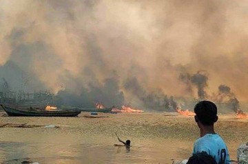 Pessoas olhando para casas em chamas no local de um  ataque aéreo realizado pelos militares de Mianmar -  (crédito: Handout / Arakan Army/ AFP)