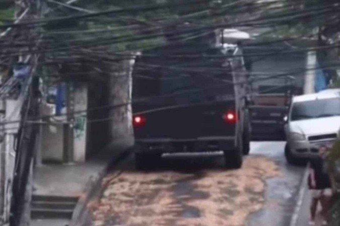 Blindado da PMRJ tenta manobrar no alto da ladeira, mas rodas começam a patinar por causa do óleo despejado no asfalto pelos traficantes. Carro perde aderência e desce sem controle