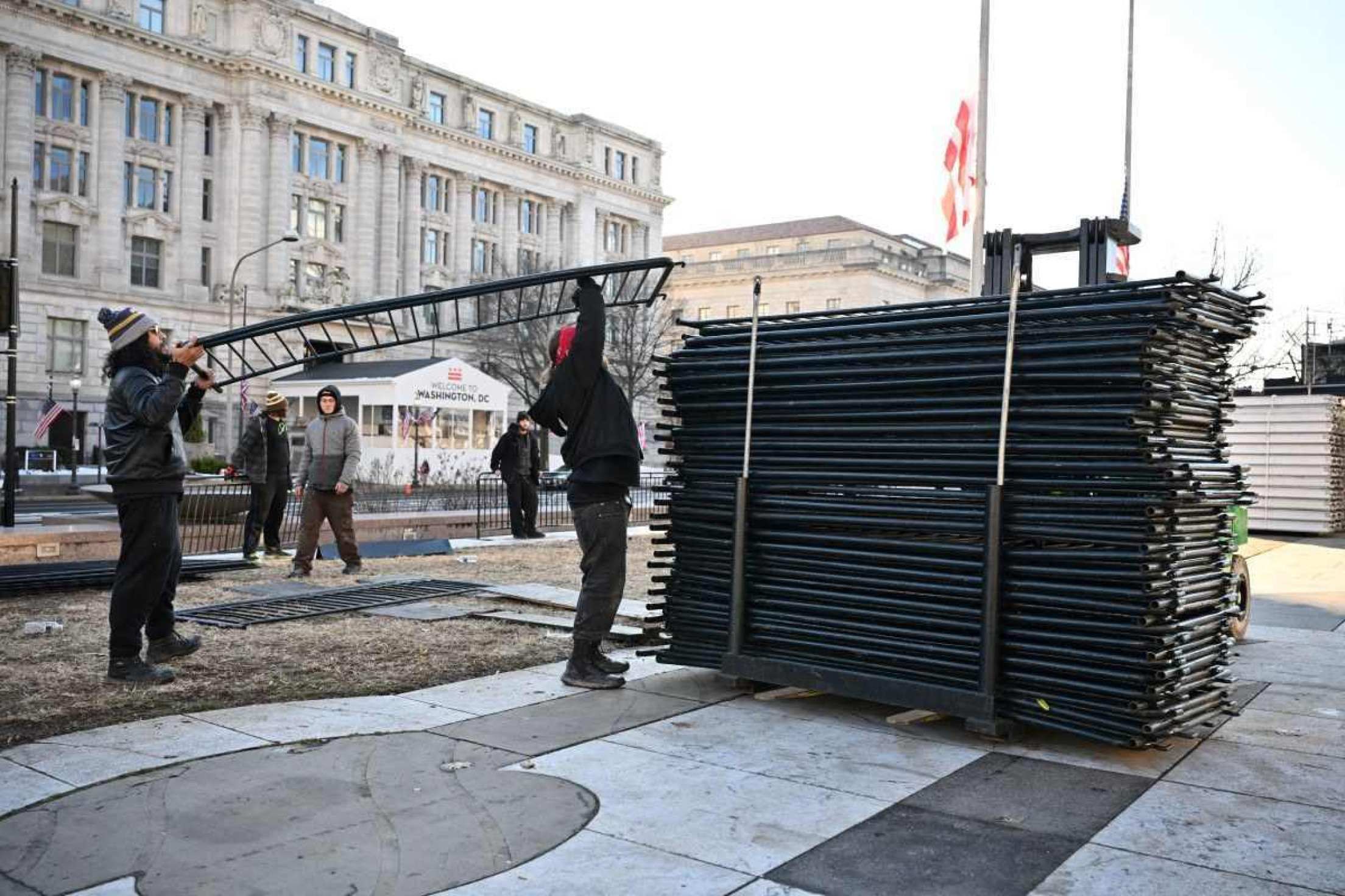 Trabalhadores removem barreiras ao longo da rota do desfile na Pennsylvania Avenue em Washington, DC, em 18 de janeiro de 2025, enquanto a capital dos EUA se prepara para a posse do presidente eleito dos EUA, Donald Trump. Donald Trump confirmou que sua posse como presidente dos EUA em 20 de janeiro será em um local fechado devido ao clima congelante esperado, minando as esperanças do republicano de um espetáculo grandioso para dar início ao seu segundo mandato. (Foto de ANGELA WEISS / AFP)