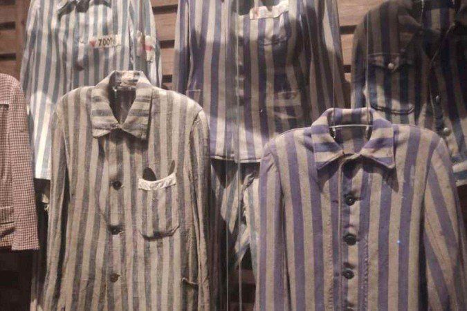 Uniformes originais de prisioneiros do campo de extermínio de Auschwitz expostos em vitrine no Yad Vashem 
