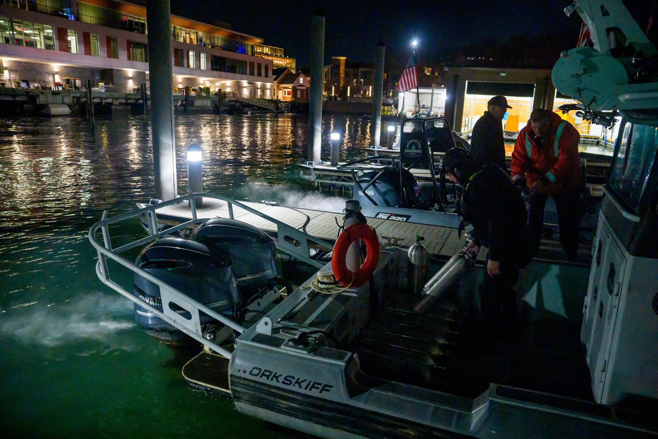 Uma equipe de resposta a emergências com a polícia de Washington, DC Fire e EMS e DC carrega equipamentos de mergulho em um barco para continuar trabalhando na cena dos destroços do avião no aeroporto de Ronald Reagan Aeroporto Ronald Reagan      