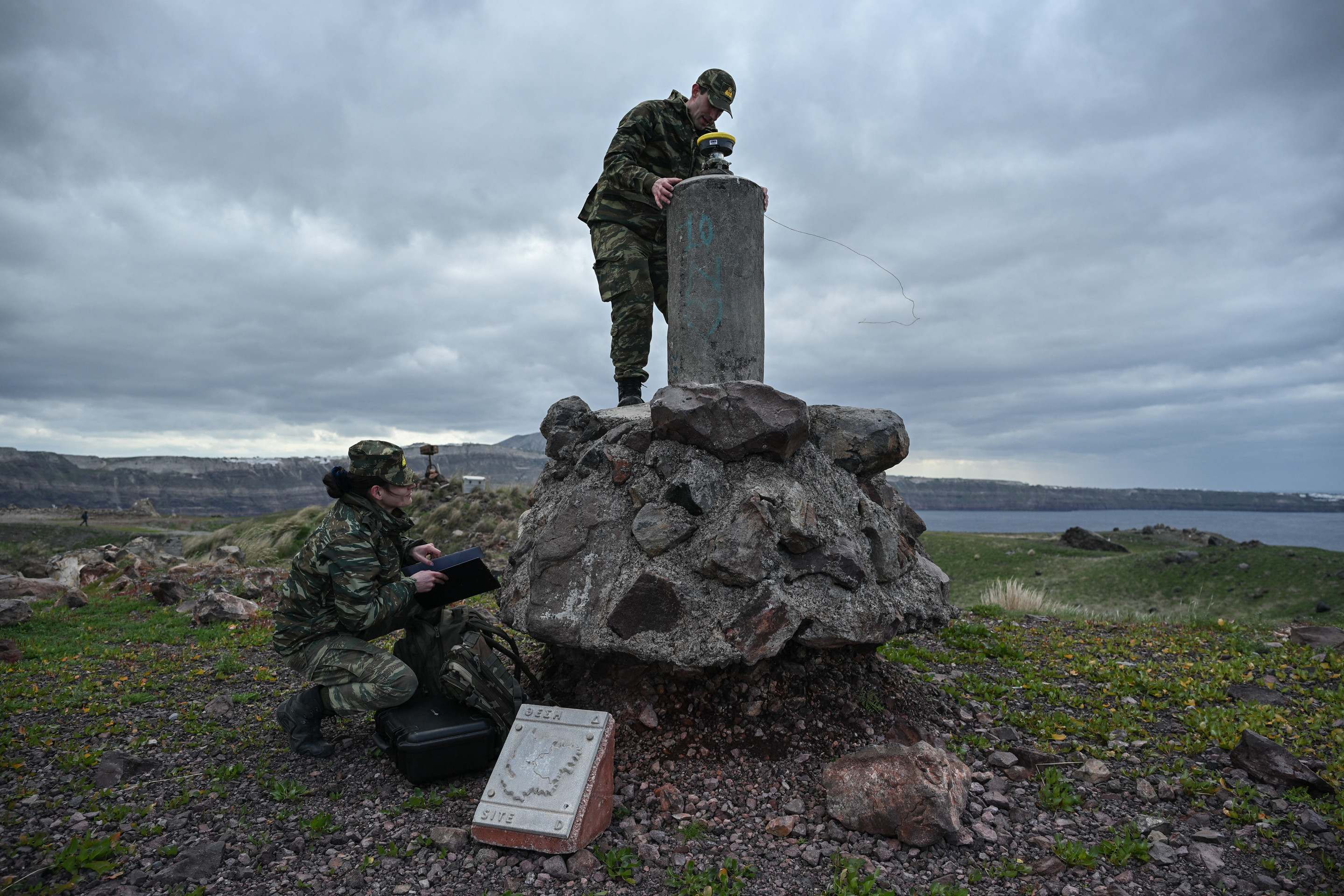 Membros do serviço geográfico militar grego fazem medições na ilha vulcânica de Santorini, Nea Kameni, para determinar se os tremores causaram alguma mudança estrutural      