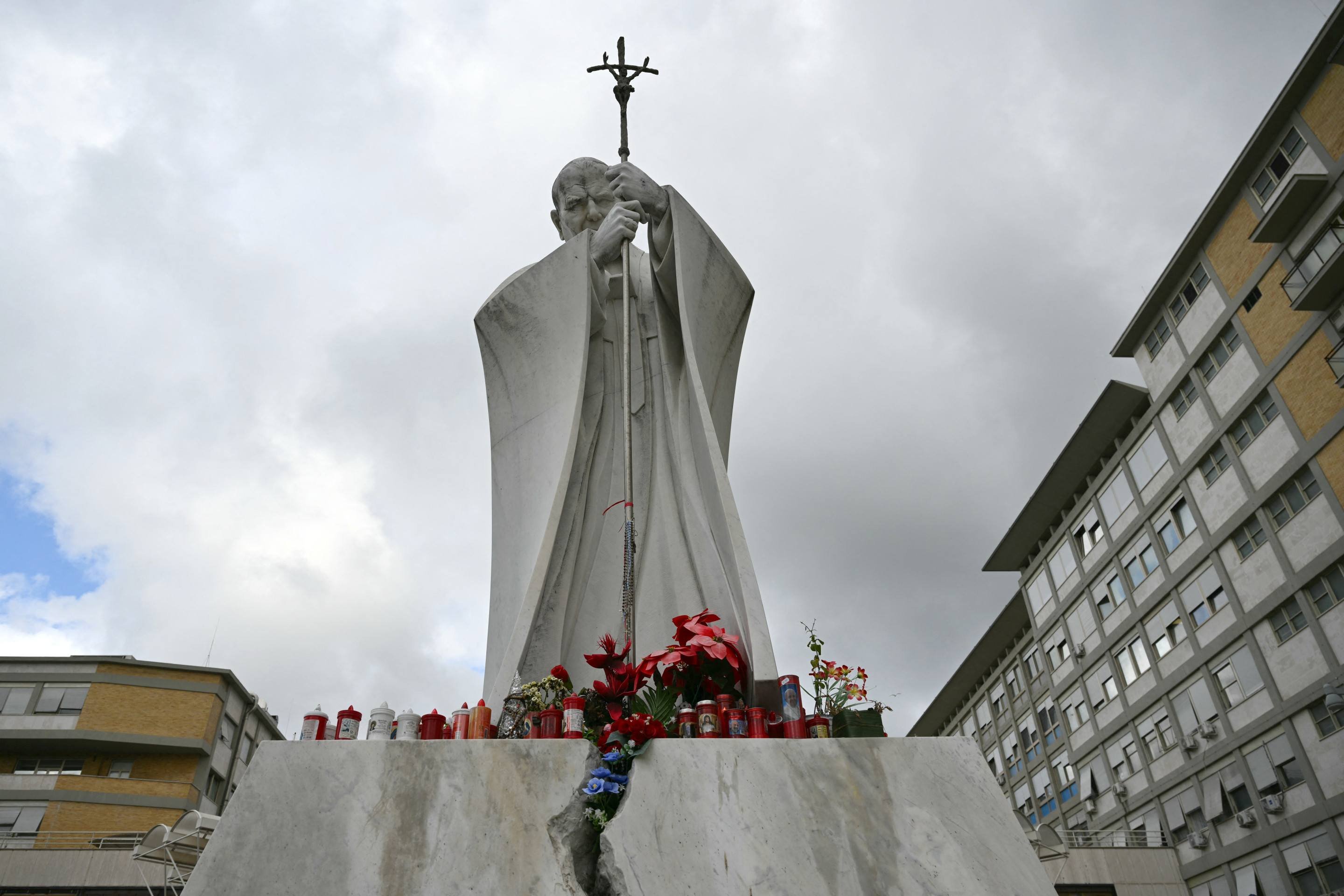 Fiéis fazem uma corrente de oração e acendem velas aos pés da estátua do Papa João Paulo II, localizada em frente o hospital       