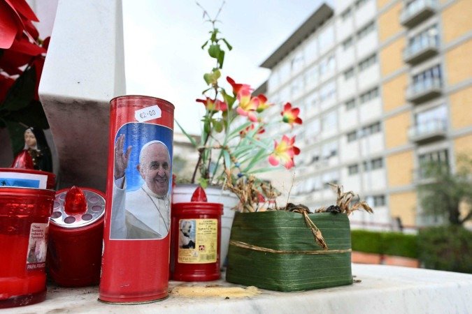 Fiéis fazem uma corrente de oração e acendem velas aos pés da estátua do Papa João Paulo II, localizada em frente o hospital - (crédito: Filippo MONTEFORTE / AFP) Fiéis fazem uma corrente de oração e acendem velas aos pés da estátua do Papa João Paulo II, localizada em frente o hospital - (crédito: Filippo MONTEFORTE / AFP)
