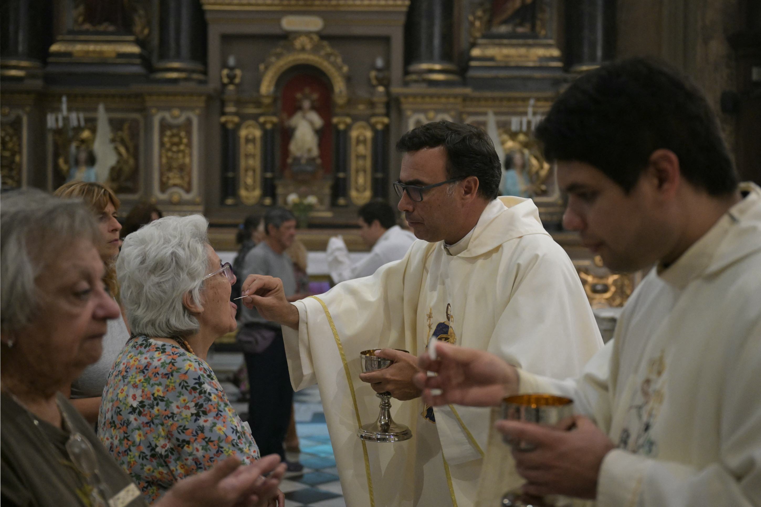 O padre Martin Bourdieu celebra uma missa ao lado de uma pintura do Papa Francisco na Basílica de San José de Flores para rezar por sua saúde em Buenos Aires em 19 de fevereiro de 2025.      