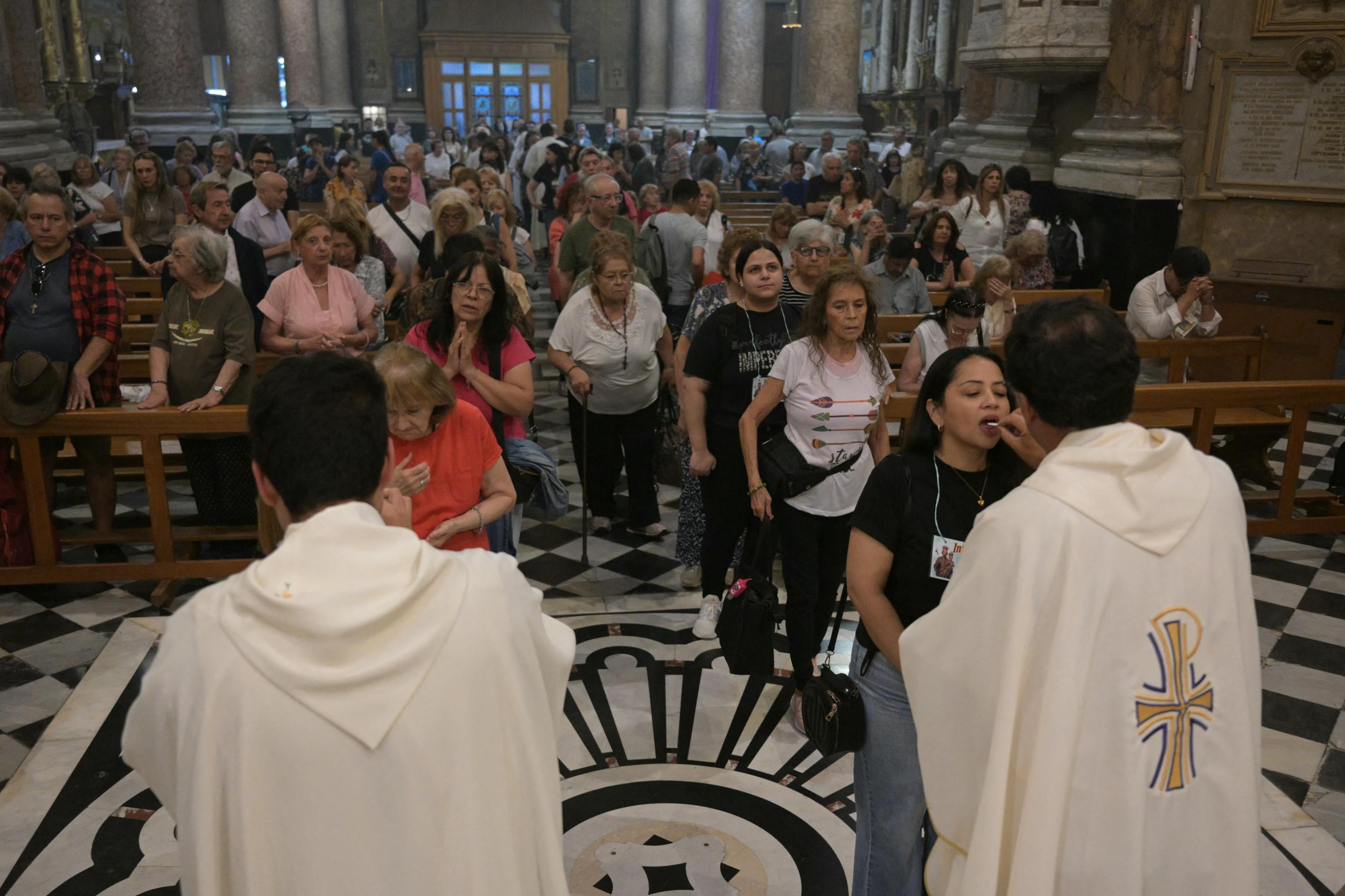 O padre Martin Bourdieu celebra uma missa ao lado de uma pintura do Papa Francisco na Basílica de San José de Flores para rezar por sua saúde em Buenos Aires em 19 de fevereiro de 2025.      