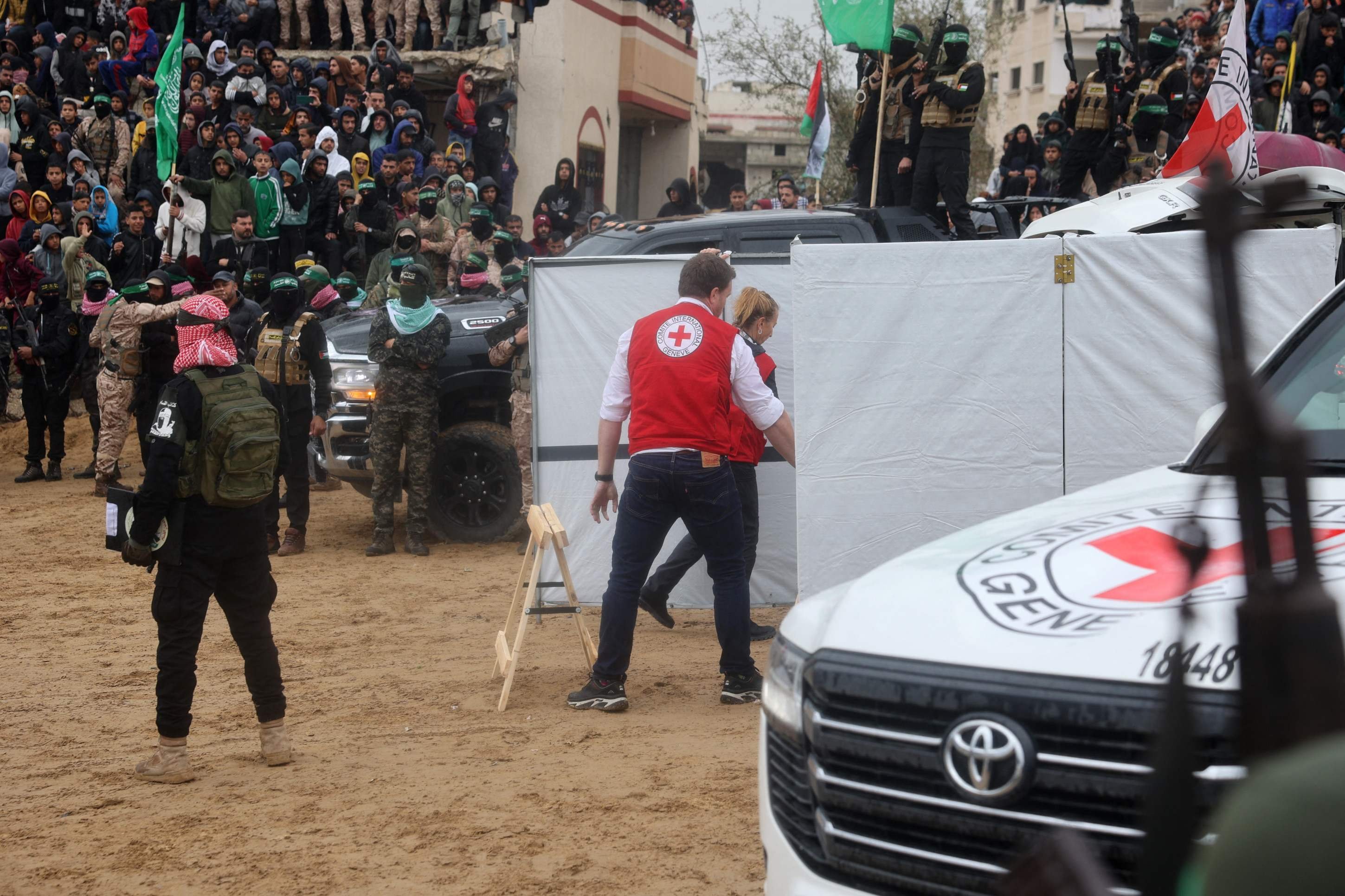 Militantes armados do Hamas estão ao lado de um veículo da Cruz Vermelha no local da entrega dos corpos de quatro reféns israelenses em Khan Yunis, no sul de Gaza, em 20 de fevereiro de 2025