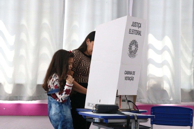 Eleitora e filha na urna. Mulheres são sub-representadas nos espaços de poder e convivem com a violência política - (crédito: Rovena Rosa/Agência Brasil) Eleitora e filha na urna. Mulheres são sub-representadas nos espaços de poder e convivem com a violência política - (crédito: Rovena Rosa/Agência Brasil)