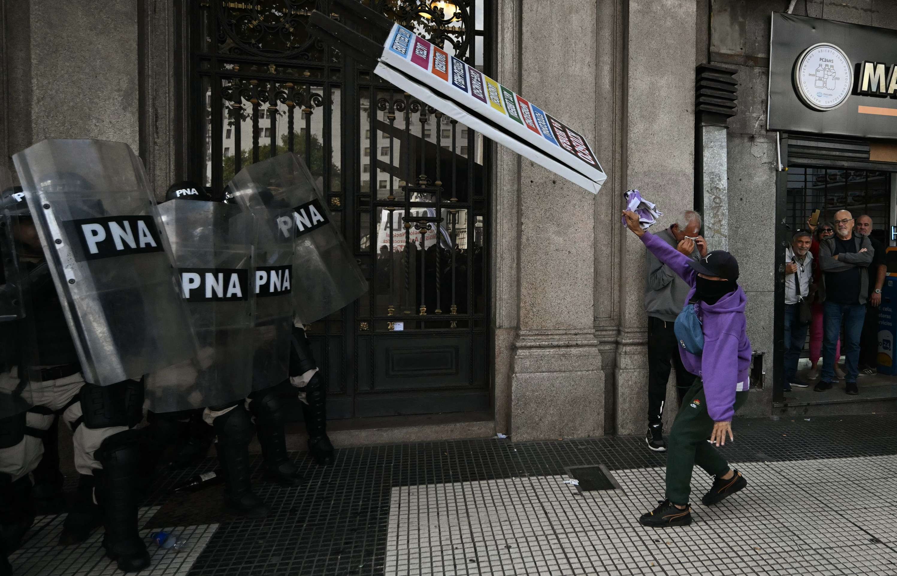  A demonstrator clashes with police during a protest of pensioners supported by football fans against the government of President Javier Milei in Buenos Aires on March 12, 2025. (Photo by Luis ROBAYO / AFP)       