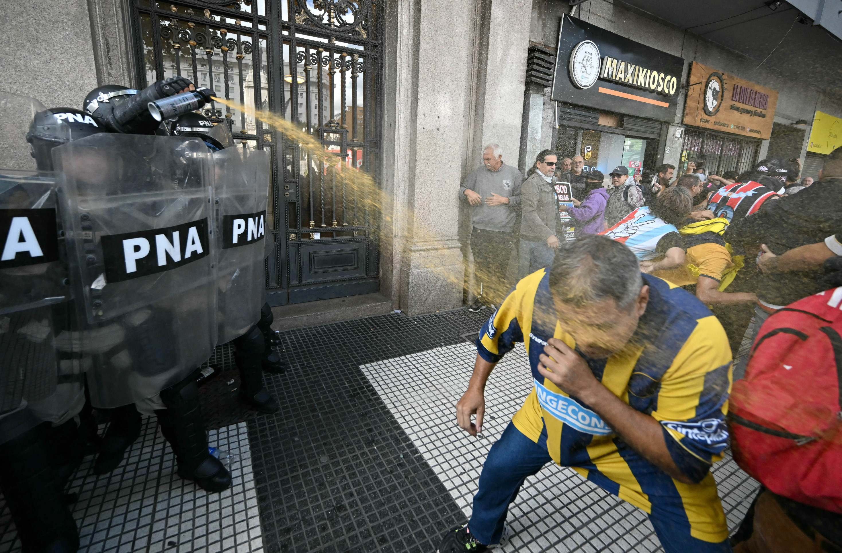  A police officer uses pepper spray on a supporter of Rosario Central during a protest of pensioners supported by football fans against the government of President Javier Milei in Buenos Aires on March 12, 2025. (Photo by Luis ROBAYO / AFP)       