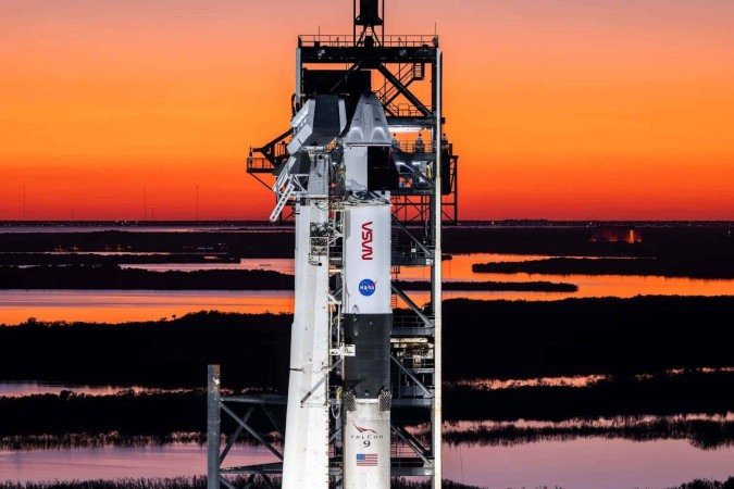 Um foguete SpaceX Falcon 9 com a nave espacial Dragon da empresa no topo é visto durante o pôr do sol na plataforma de lançamento no Complexo de Lançamento 39A no Centro Espacial Kennedy da NASA na Flórida 