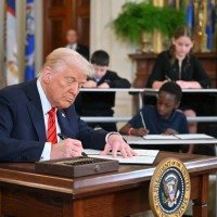 Donald Trump firma o documento no Salão Leste da Casa Branca, acompanhado de estudantes: promessa de campanha  -  (crédito: Mandel Ngan/AFP)