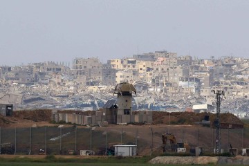 Uma torre de vigia militar israelense fica ao longo da fronteira sul de Israel com o norte da Faixa de Gaza, tendo como pano de fundo edifícios destruídos durante a guerra entre Israel e o Hamas, em 20 de março de 2025       -  (crédito: GIL COHEN-MAGEN/AFP)