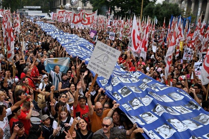 Manifestantes carregam faixa com as fotografias dos rostos de desaparecidos durante a ditadura militar, em marcha na capital, Buenos Aires 