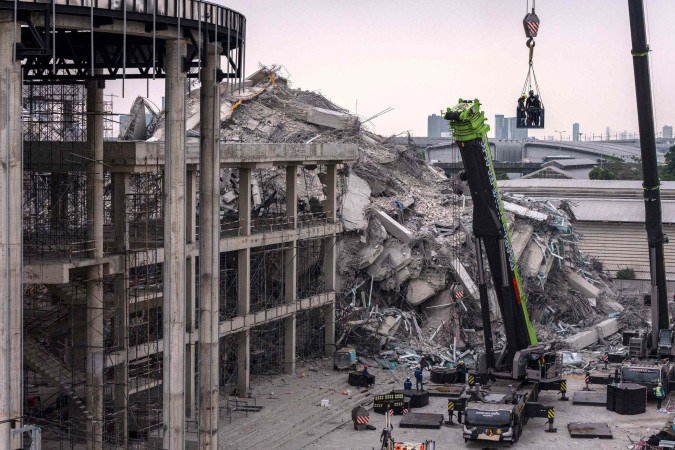 Equipes de resgate são içadas em um guindaste durante operações de busca e salvamento no local do desabamento de um prédio em construção em Bangkok em 31 de março de 2025       -  (crédito: Chanakarn Laosarakham/AFP)