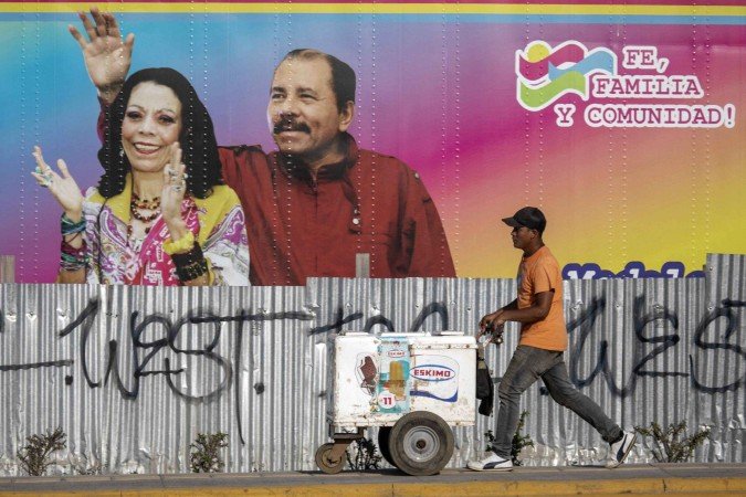Vendedor de sorvete a em frente a outdoor com as fotos de Ortega e Murillo, em Manágua - (crédito: Inti Ocon/AFP) Vendedor de sorvete a em frente a outdoor com as fotos de Ortega e Murillo, em Manágua - (crédito: Inti Ocon/AFP)