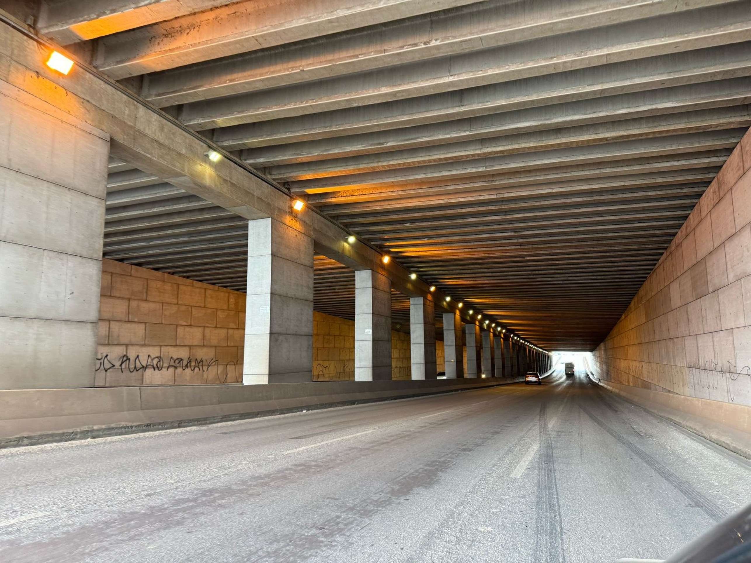 Túnel do aeroporto antes da iluminação de LED, com lâmpadas amarelas. 