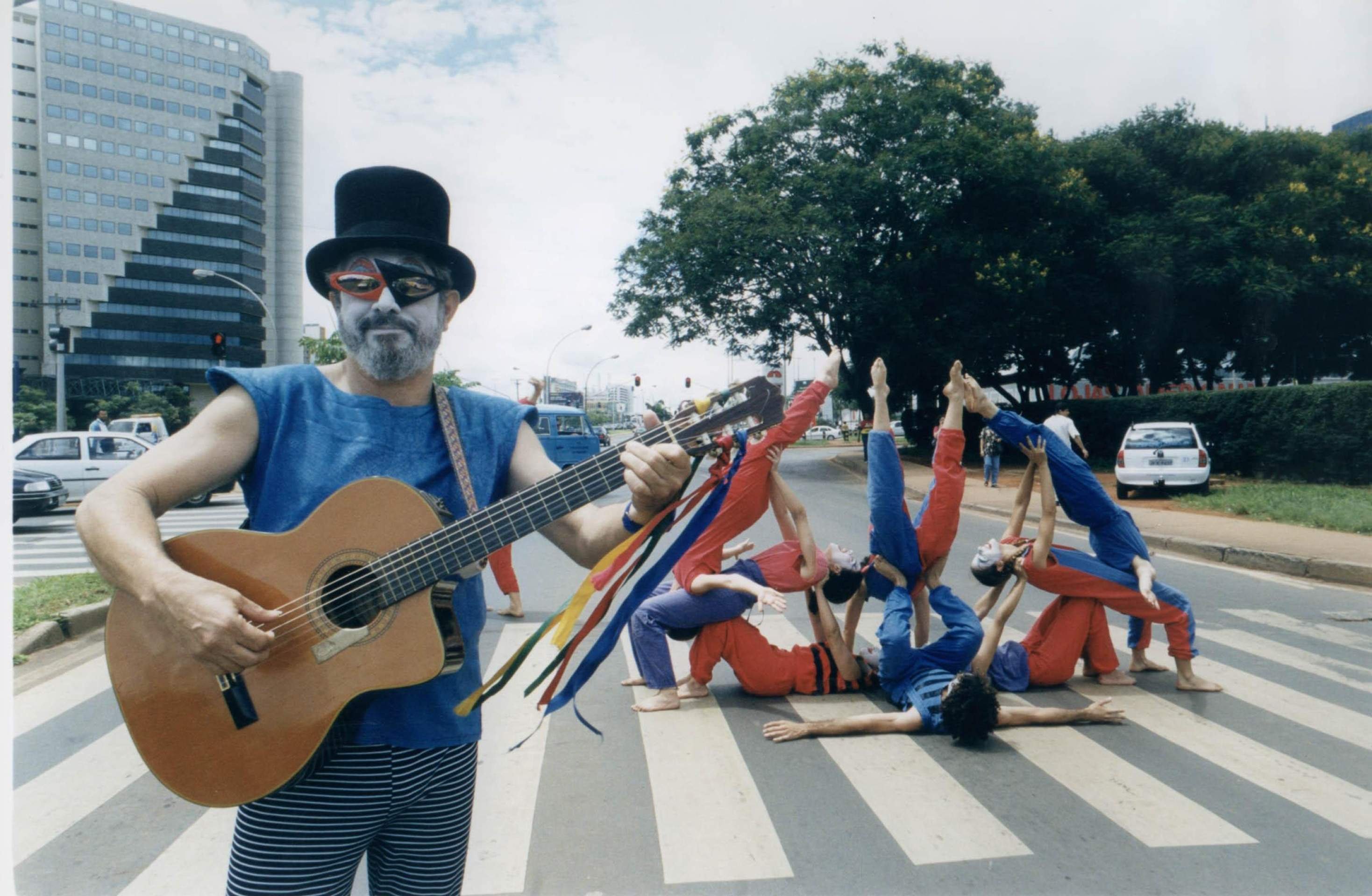  05/12/2000. Crédito: Jorge Cardoso/CB/D.A Press. Brasil. Brasília - DF. Ator Ary Pára-Raios, no meio da pista com um violão faz uma performance, tendo ao fundo o restante da trupe Esquadrão da vida.       Caption 