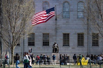 Manifestantes protestam contra os ataques de Trump à universidade, diante de estátua de John Harvard, no câmpus de Cambridge (Massachusetts) -  (crédito: Joseph Prezioso/AFP)