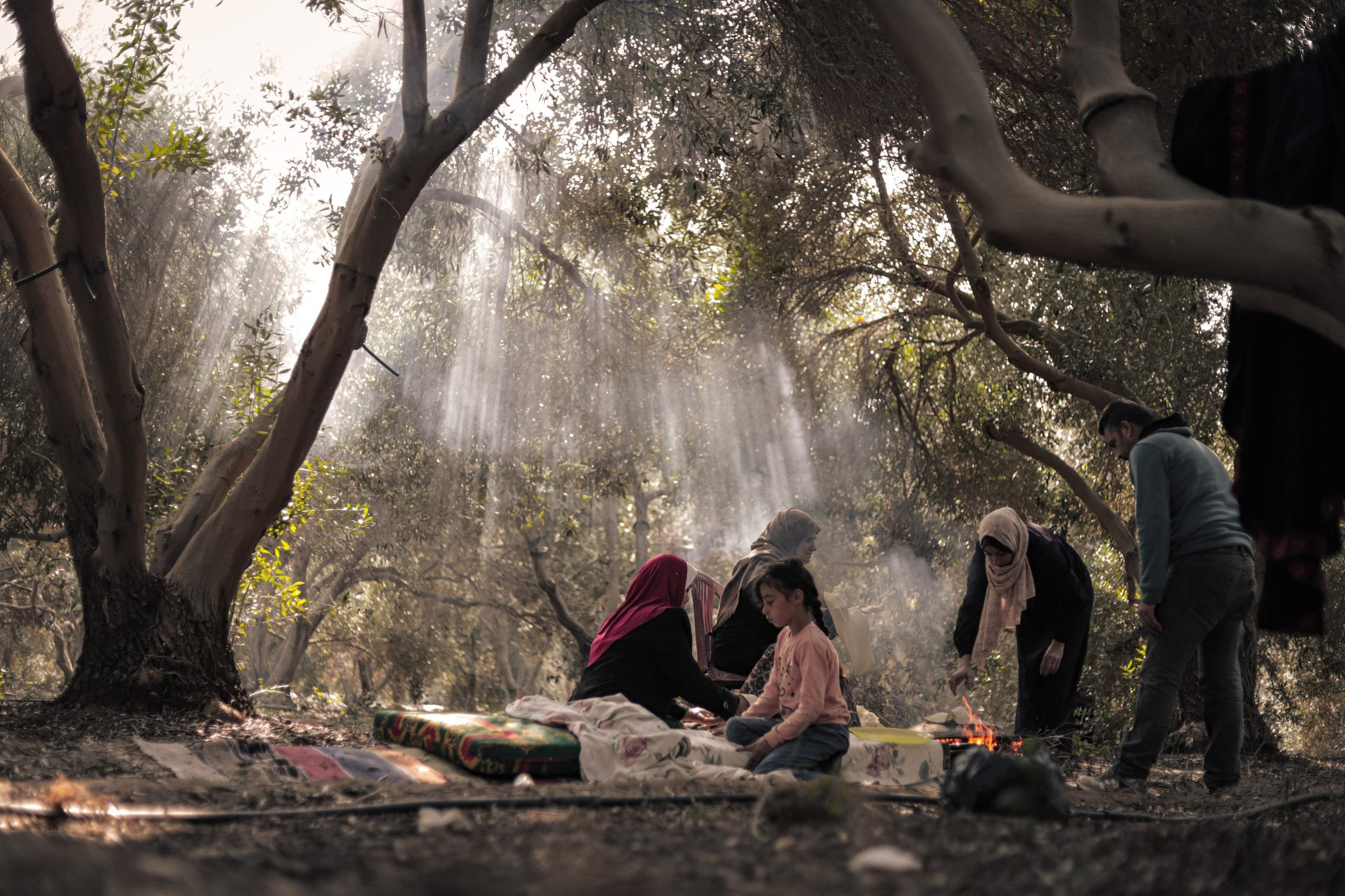 Sequência de imagens feitas por Fatma: família prepara pão, em Az-Zawaida, na região central de Gaza; homem chora diante de cadáver em mortalha; criança sorri entre os escombros; mulheres se abraçam, em meio à dor