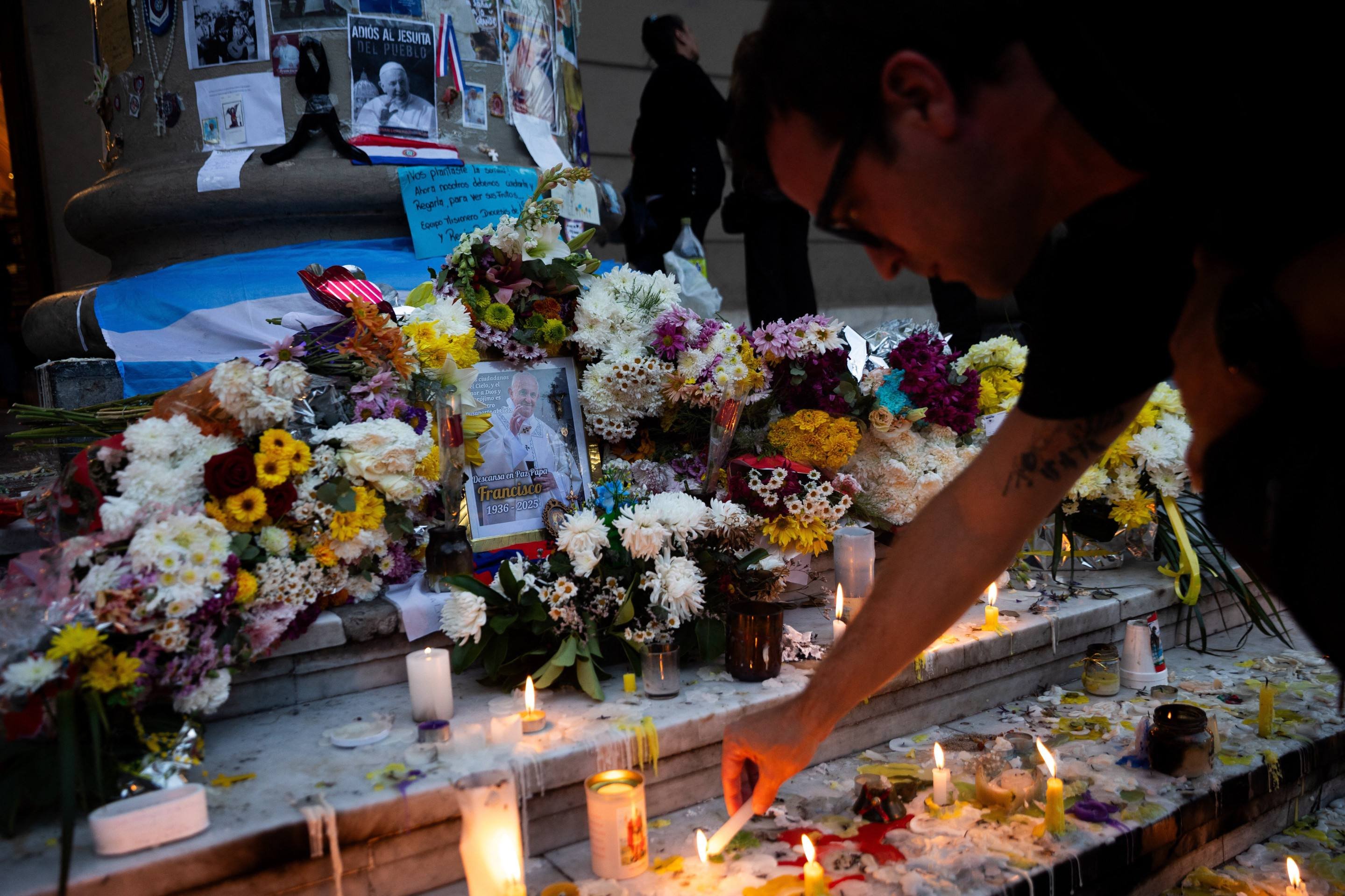 Um homem acende uma vela em um altar improvisado em frente à Catedral de Buenos Aires após uma missa em homenagem ao falecido Papa Francisco em 23 de abril de 2025      