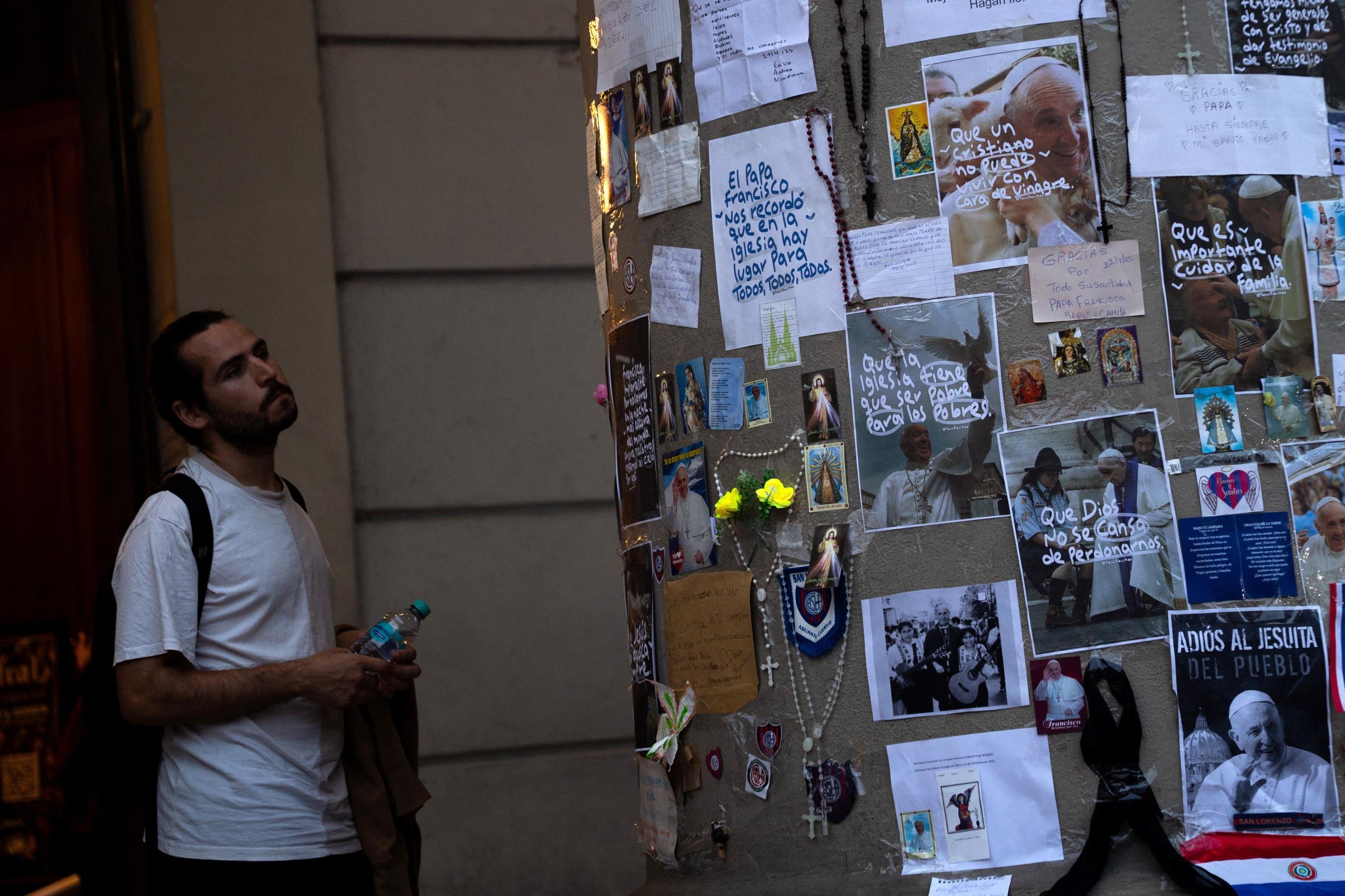 Um homem observa fotos do falecido Papa Francisco deixadas pelos fiéis em um altar improvisado em frente à Catedral de Buenos Aires, após uma missa em 23 de abril de 2025      