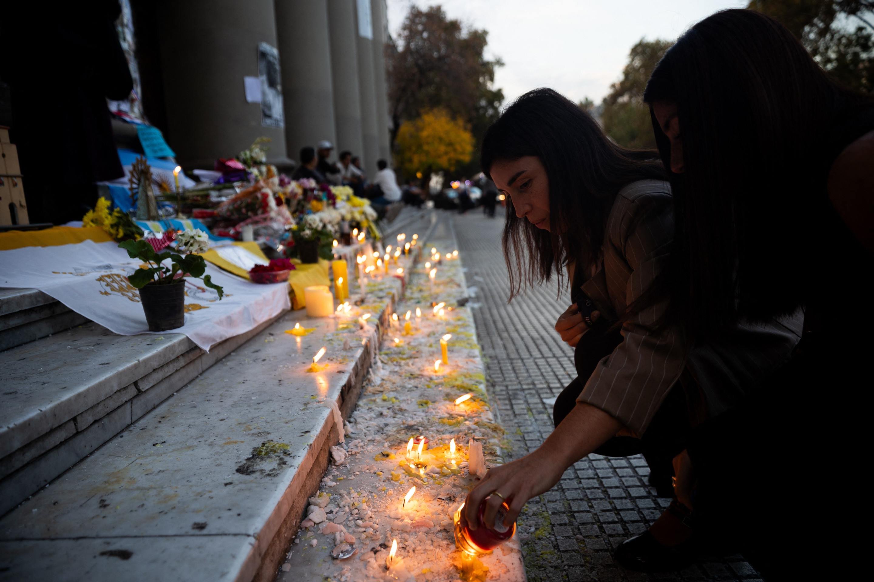Uma mulher acende uma vela em um altar improvisado em frente à Catedral de Buenos Aires após uma missa em homenagem ao falecido Papa Francisco em 23 de abril de 2025