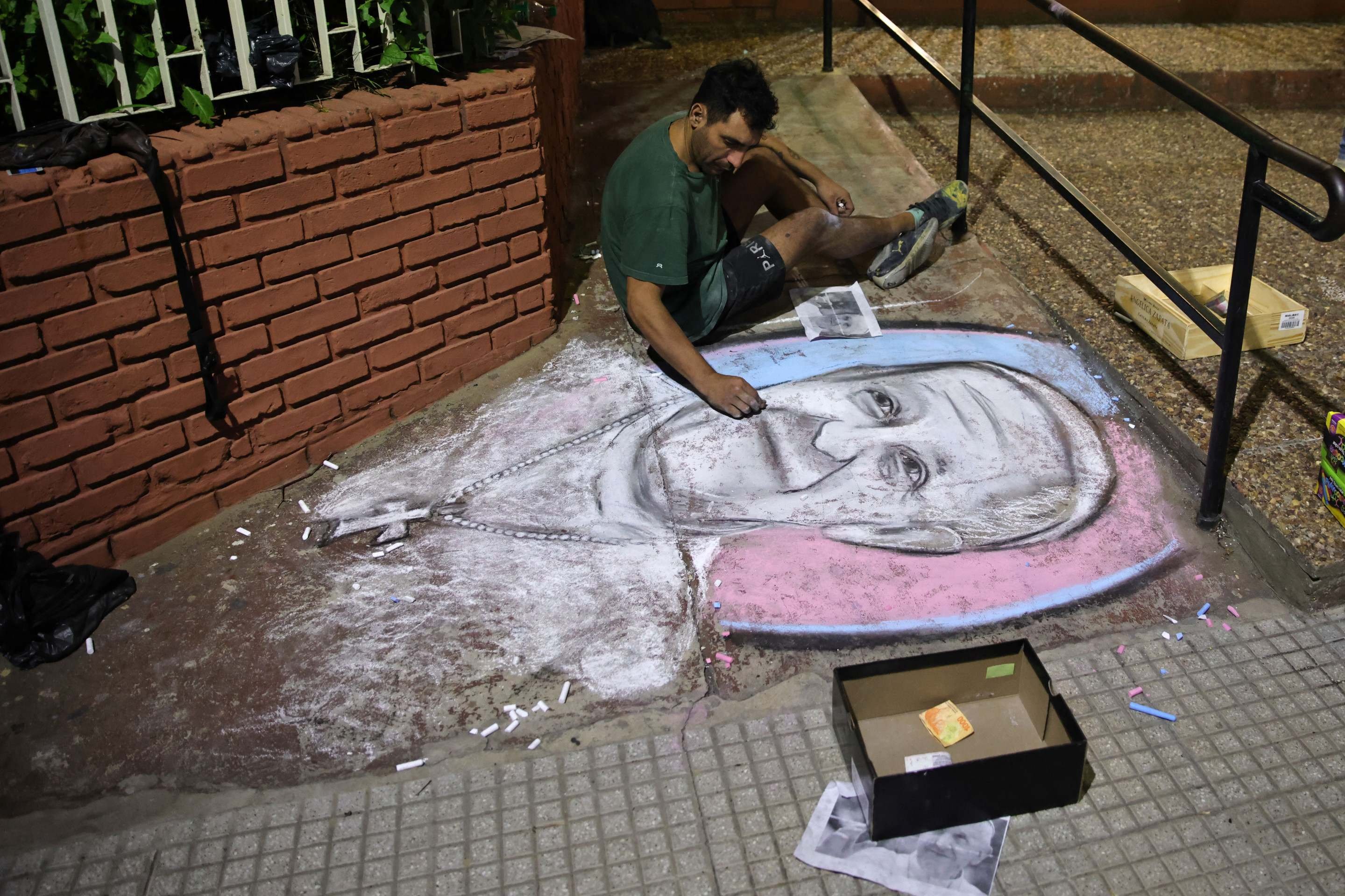 Um homem desenha o rosto do falecido Papa Francisco em uma rua em frente ao Oratório San Antonio, local de fundação do clube de futebol San Lorenzo, em Buenos Aires, em 23 de abril de 2025