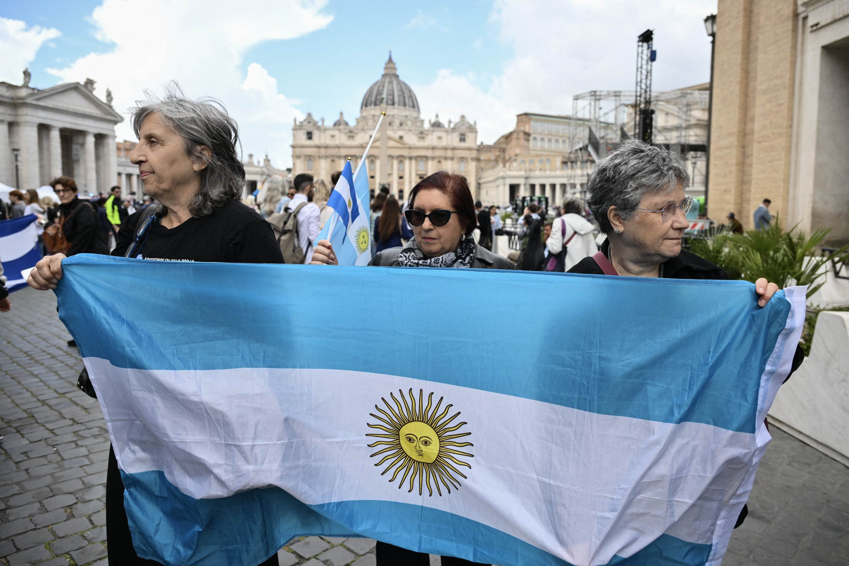 Pessoas seguram a bandeira da Argentina na Via della Conciliazione, com a Basílica de São Pedro ao fundo, perto do Vaticano, em Roma, em 24 de abril de 2025      