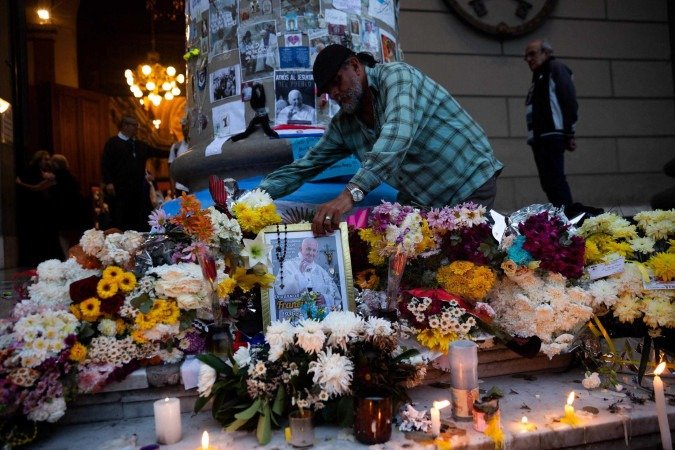 Um homem deposita um retrato do falecido Papa Francisco em um altar improvisado em frente à Catedral de Buenos Aires, após uma missa em 23 de abril de 2025       -  (crédito: TOMAS CUESTA/AFP)