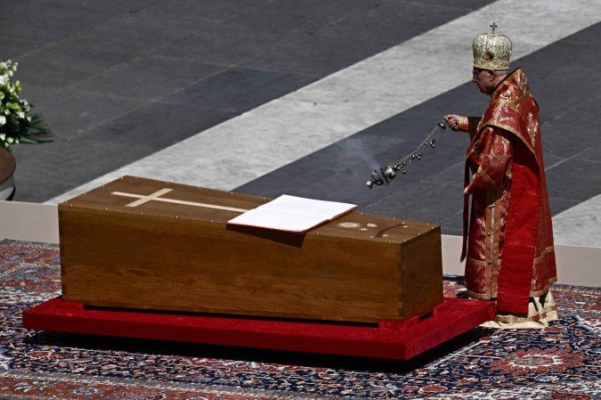 Um membro do clero caminha ao lado do caix&atilde;o do papa Francisco com o livro dos evangelhos exposto durante o funeral da Pra&ccedil;a de S&atilde;o Pedro