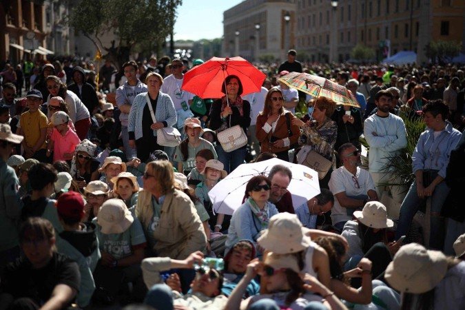 Pessoas assistem a um culto religioso em um telão na Via della Conciliazione, antes da cerimônia fúnebre do Papa Francisco, perto do Vaticano, em Roma, em 26 de abril de 2025      