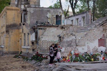 Moradores colocam flores em um prédio residencial destruído após um ataque de mísseis russos em Kiev em 25 de abril de 2025     -  (crédito: Tetiana DZHAFAROVA / AFP)