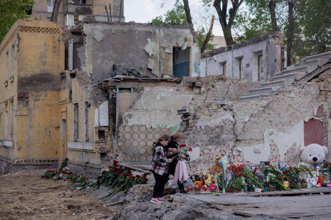 Moradores colocam flores em um prédio residencial destruído após um ataque de mísseis russos em Kiev em 25 de abril de 2025 - (crédito: Tetiana DZHAFAROVA / AFP) Moradores colocam flores em um prédio residencial destruído após um ataque de mísseis russos em Kiev em 25 de abril de 2025 - (crédito: Tetiana DZHAFAROVA / AFP)