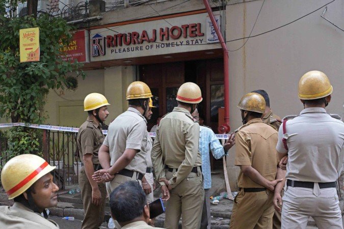  Police officials and firefighters gather at the entrance of the Rituraj Hotel where a fire brokeout, in Kolkata on April 30, 2025. A fierce fire ripped through a hotel in the Indian city of Kolkata killing at least 15 people, police said on April 30, with some clambering out of windows and onto the rooftop to escape. (Photo by Dibyangshu SARKAR / AFP)       Caption 