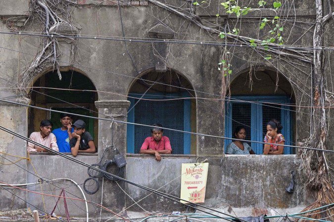 Onlookers stand in a balcony as they look at the Rituraj Hotel where a fire brokeout, in Kolkata on April 30, 2025. A fierce fire ripped through a hotel in the Indian city of Kolkata killing at least 15 people, police said on April 30, with some clambering out of windows and onto the rooftop to escape. (Photo by Dibyangshu SARKAR / AFP)       Caption 
