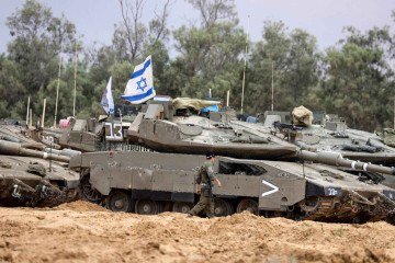 Um soldado israelense caminha perto de tanques posicionados perto da fronteira de Israel com a Faixa de Gaza em 4 de maio de 2025       -  (crédito: Menahem KAHANA/AFP)