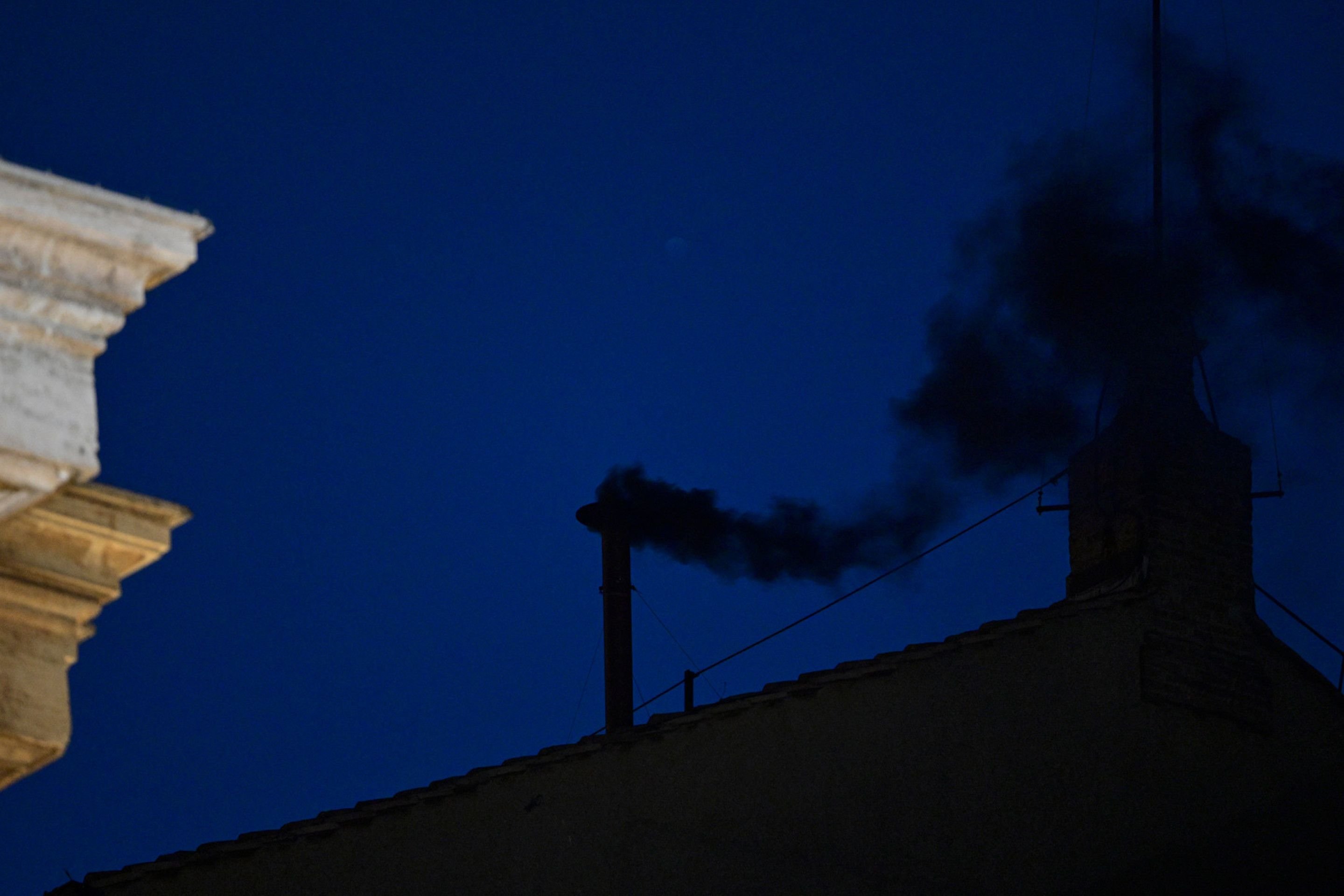  This photograph shows black smoke rising from the chimney of the Sistine Chapel signalling that cardinals failed to elect a new pope in the first ballot of their conclave in the Vatican on May 7, 2025. (Photo by Tiziana FABI / AFP)     