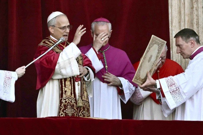 O recém-eleito Papa Leão XIV, Robert Prevost (E), discursa para a multidão na varanda principal da galeria central da Basílica de São Pedro pela primeira vez, após o encerramento do conclave pelos cardeais, no Vaticano, em 8 de maio de 2025. Robert Francis Prevost foi eleito na quinta-feira o primeiro papa dos Estados Unidos, anunciou o Vaticano. Moderado, próximo do Papa Francisco e missionário no Peru durante anos, ele se torna o 267º pontífice da Igreja Católica, adotando o nome papal de Leão XIV. - (crédito: Filippo MONTEFORTE / AFP) O recém-eleito Papa Leão XIV, Robert Prevost (E), discursa para a multidão na varanda principal da galeria central da Basílica de São Pedro pela primeira vez, após o encerramento do conclave pelos cardeais, no Vaticano, em 8 de maio de 2025. Robert Francis Prevost foi eleito na quinta-feira o primeiro papa dos Estados Unidos, anunciou o Vaticano. Moderado, próximo do Papa Francisco e missionário no Peru durante anos, ele se torna o 267º pontífice da Igreja Católica, adotando o nome papal de Leão XIV. - (crédito: Filippo MONTEFORTE / AFP)